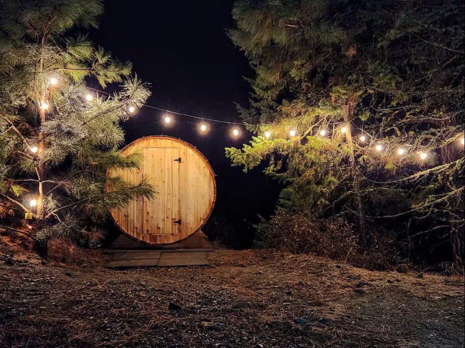 Barrel sauna in the forest with string lights